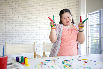 Wall Mural - young teenage girl showing painted hands and doing victory sign, drawing a picture on paper