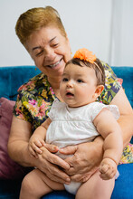 Grandma Latina Woman With Her Granddaughter On Her Lap Smiling. Vertical Photo