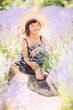 Vertical portrait dreamy cute little girl with haircut in big summer hat in lavender field with purple flowers around in sunny summer day. Summer in Provence. Travel. Child in lavender. Closed eyes