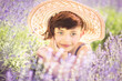 Portrait of sad cute little girl with haircut in big summer hat in lavender field with purple flowers around in sunny summer day. Summer in Provence. Travel. Child in lavender. Sad thinking