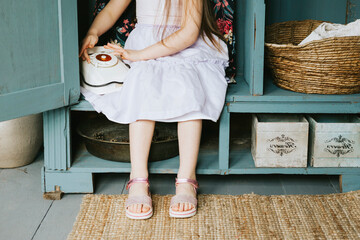 little cute Armenian girl sit in retro vintage wardrobe and playing hide-and-seek in country house and having fun with disk analog phone, concept of simple life and spring