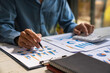 © crizzystudio - Businessmen hold graph pens and use a calculator for the company's improvement plan.