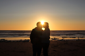 Silhouette of a kissing couple on a beach at sunset