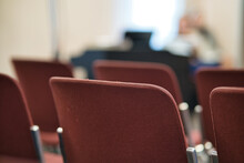 Selective Focus Shot Of Red, Empty Chairs In A Church Against A Blurry Background