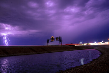 Wall Mural - View of the street against the violet lightning in the sky.