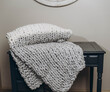 Closeup shot of the soft custom made chunky blanket on the wooden small table in the house
