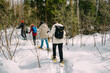© Adsloboda - Snowshoeing people in winter forest in snow. Winter outdoor activity. Trekking in snow covered landscape using snowhoes and trekking poles.