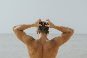 Young Spanish sporty male waring swimming goggles on the beach