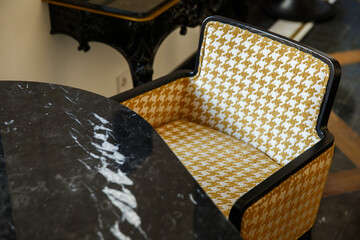 Sticker - Closeup shot of a small, armchair with yellow and white patterns near the black marble table