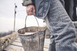 © Golovchenko Dmytro - A man carries a metal bucket in his hands filled with parts of the fence, house, walls and ceiling. Establishing order after hostilities on the territory of Ukraine. No war.