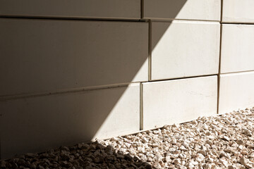 Sticker - Closeup of a tiled ceramic wall with a sunny stony pebbles floor