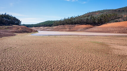 Landscape of low water and dry land in advance, severe drought in the reservoir of Portugal. Ecological disaster, soil dehydration. desert, drought,