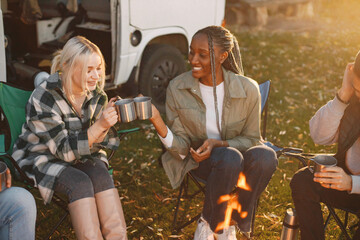 Multi racial people drink coffee by fireplace