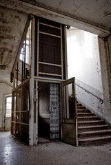 Poster - Vertical shot of the interior in an old abandoned building with an elevator and stairs