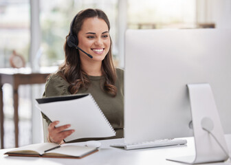 Aufkleber - Inputting new info onto the system. Shot of a young call centre agent going through paperwork while working on a computer in an office.