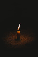 Small Candle Burning On The Soil Ground In The Dark - Light Contrast Concept