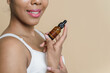 © etonastenka - Skin care. Close up black woman using collagen hydrating serum with pipette. Female model with a natural cosmetic product for hydrated, radiant and healthy facial skin. Copy space