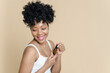 © etonastenka - Portrait of a beautiful black woman holding a bottle of moisturizing serum on a beige background. African American young woman smiling while holding a jar of oil.