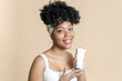 © etonastenka - Portrait of african american woman holding skin care moisturizer and smiling. Attractive black woman with beautiful skin holding a bottle of cosmetic cream mockup.
