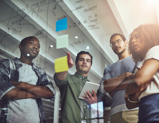 Aufkleber - I think thats what we need to focus on. Low angle shot of a group of young designers planning on a glass board.