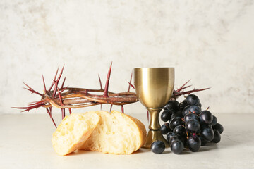 Wall Mural - Cup of wine with grapes, bread and crown of thorns on light background