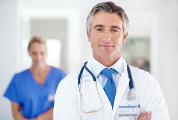 Aufkleber - You come first. Portrait of a male doctor with a colleague standing in a the background.