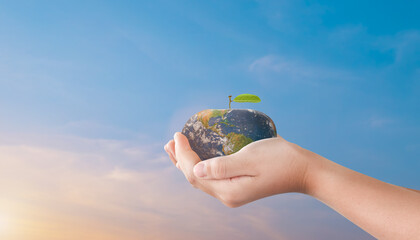 Canvas Print - child hands holding apple globe earth over blurred sunset sky background. world environment day conc