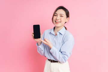 Wall Mural - Image of young Asian girl holding smartphone on pink background