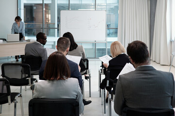 Poster - Group of contemporary economists analyzing financial documents with data while sitting in rows in front of whiteboard in auditorium