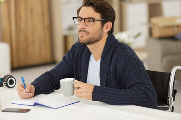 disabled man sat at a table writing in a book