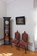 © Mint Images - A grandfather clock and two chairs in a room in a hotel.