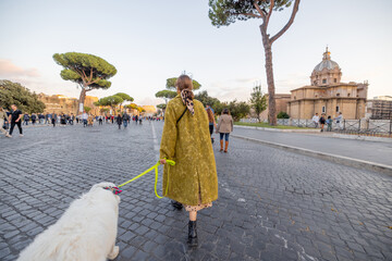 Wall Mural - Woman walking with a dog on the famous central street in Rome, taking photos on phone and enjoying old architecture during a sunset. Concept of italian lifestyle and travel