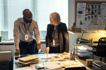 Aufkleber - Two interracial agents of FBI discussing criminal profiles at meeting in bureau while one of them pointing at photo of suspect