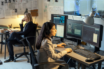 Poster - Serious female agent of intelligence service sitting in front of computer monitors in office and processing personal data of criminals