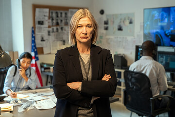 Aufkleber - Serious mature leader of criminal department in formalwear standing in office against her two young interracial subordinates