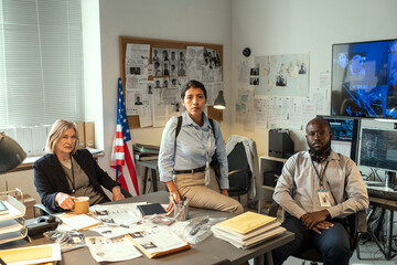 Aufkleber - Group of three interracial agents of FBI or investigators sitting by workplace in office and looking at camera at meeting