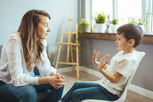 Young Female Psychologist Working With Little Boy In Office. Shot Of A Young Child Psychologist Talking With A Boy. Young Female School Psychologist Having Serious Conversation With Smart Little Boy