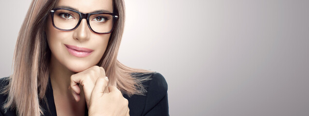 Wall Mural - Attractive businesswoman in spectacles and suit. Panorama banner on grey background with copy space