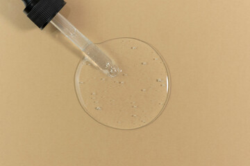 The texture of serum, oil, fluid or gel for the face with a pipette on a beige background. Wellness and beauty concept