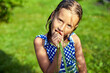 A young girl holds and eat a carrot that she picked from her family's garden