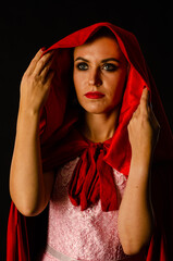 Wall Mural - beautiful woman red cloak with red flowers roses in studio. Woman Red Riding Hood. Dramatic and fantastic shooting,fashionable toning. Like a princess