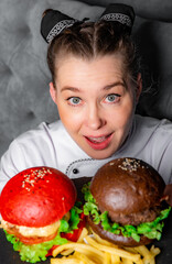 woman chef with two burger on dark background in cafe