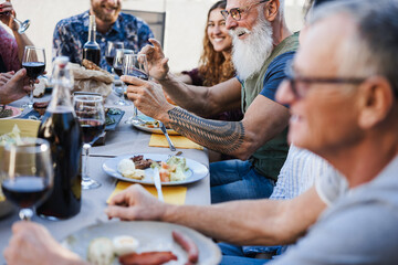 Wall Mural - Family people eating at barbecue dinner outdoor - Focus on senior hand holding glass of wine