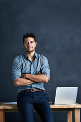 Hes all about launching ideas onto the path of success. Portrait of a handsome young businessman standing in front of a desk against a dark background.