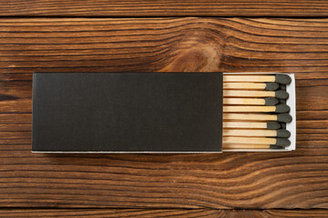 Wall Mural - top view black color matchbox with black match sticks on a wood table