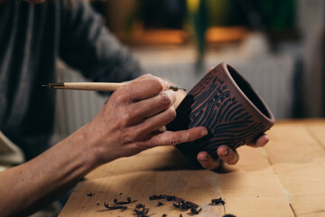 woman are making pottery in her workshop. she is carving crockery