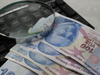 Turkish paper banknotes and coins on wooden background. Economic research, finance and analysis with magnifying glass.