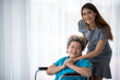 © chokniti - health insurance concept, young Asian woman are visit her senior family patient at hospital room, grandmother sitting on wheelchair are sick and having health care support by doctor and nurse
