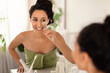 Pretty smiling millennial woman in towel using eyelash curler near mirror at home, copy space