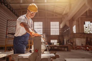 Male builder using woodworking machine in workshop